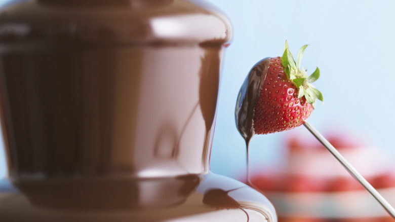 A piece of strawberry dipped into chocolate fondue fountain