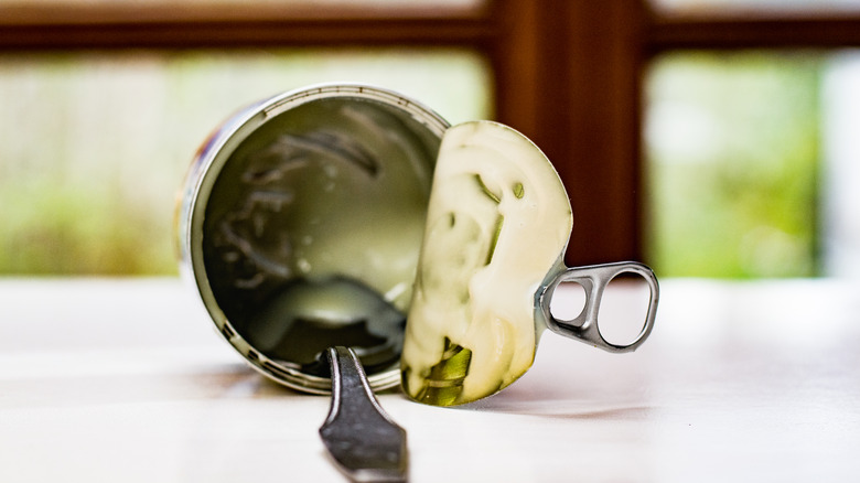 An opened can of condensed milk with a spoon inside