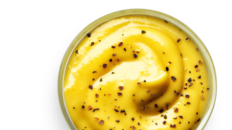 A bowl of honey mustard on a white background.