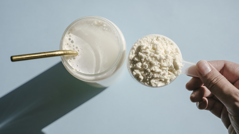 Glass of milk beside a scoop of whey protein powder