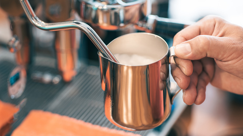 Barista steaming a pitcher of milk