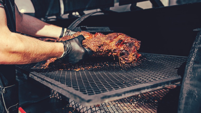 person putting meat in smoker