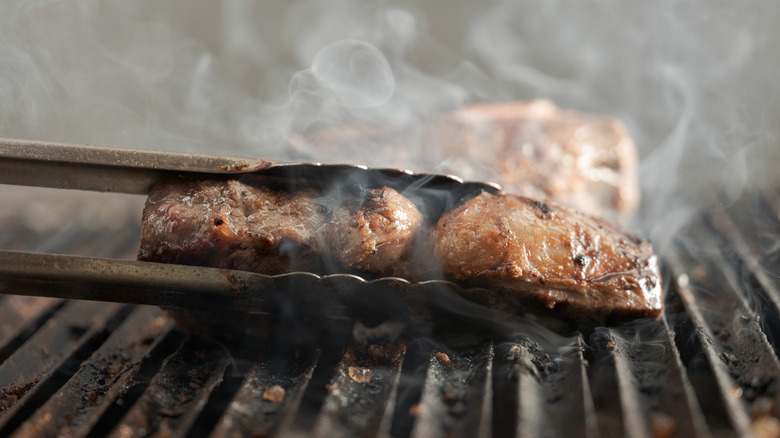 smoked meat held in tongs