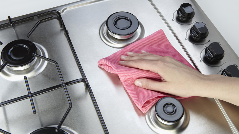 Person cleans stovetop with rag