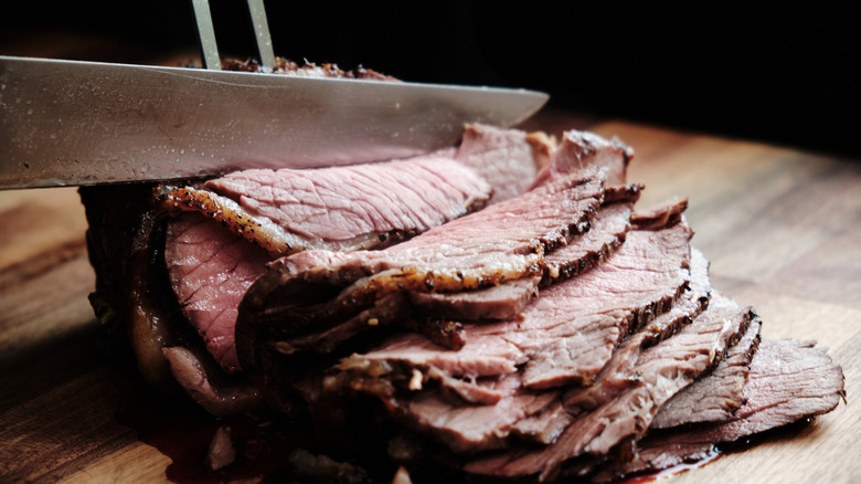 A knife slicing through roast beef