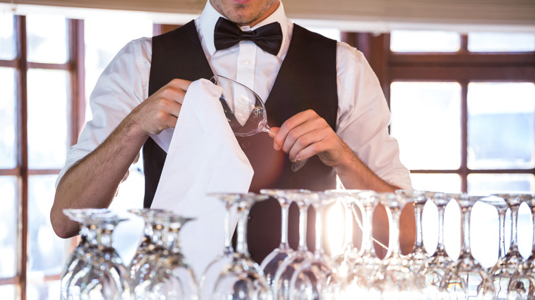 formal bartender cleans glassware