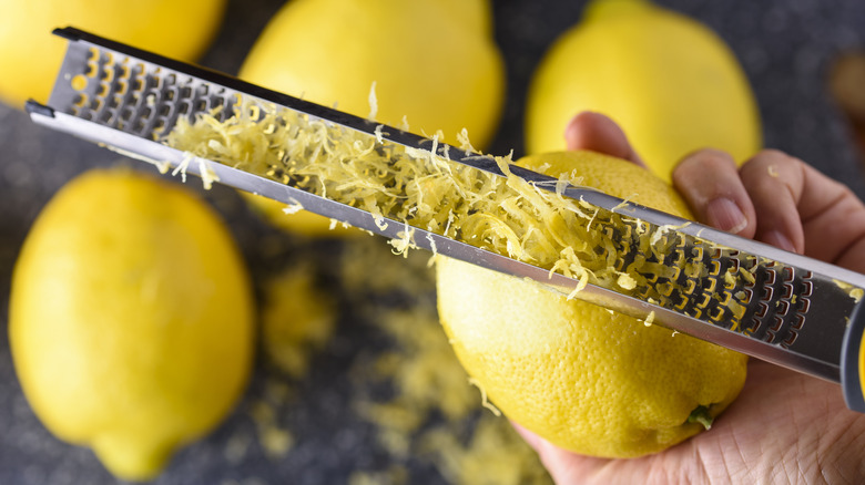Hand zesting a lemon.