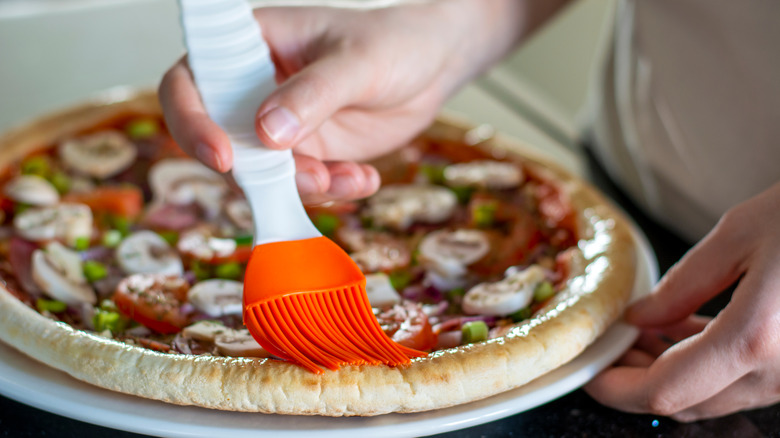 Brushing pizza crust with oil