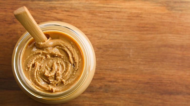 Jar of peanut butter with a wooden spoon