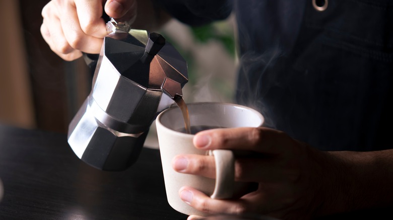 Moka pot pouring coffee into mug