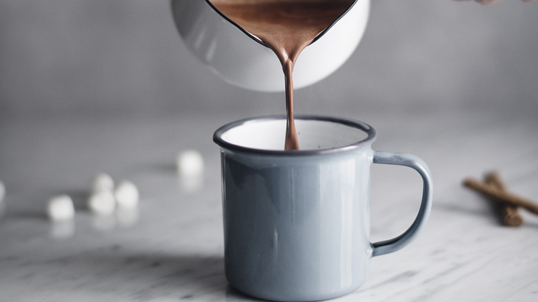 Milk based hot chocolate being poured into a mug