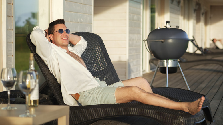 man relaxing with a Weber grill