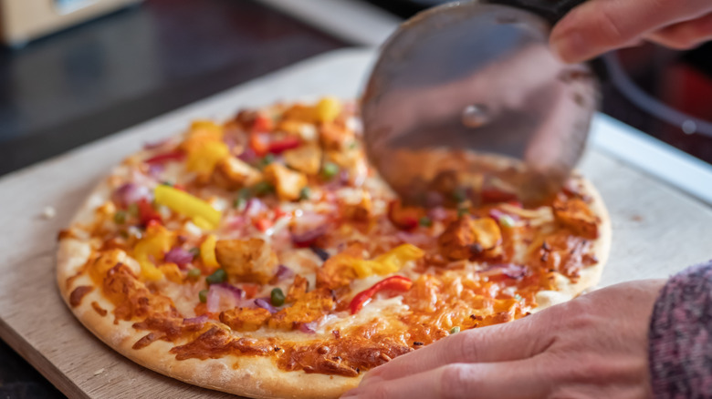 Person slices a cooked frozen pizza