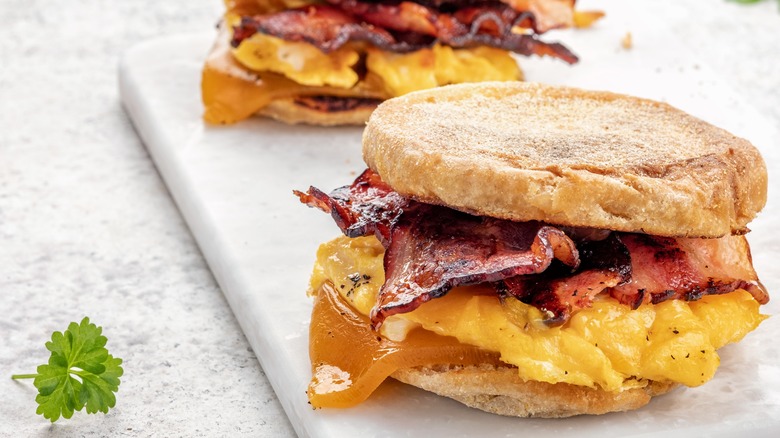 Two breakfast sandwiches on a marble cutting board with parsley garnish