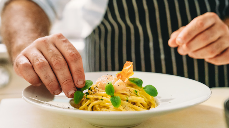 chef using hands to plate dish