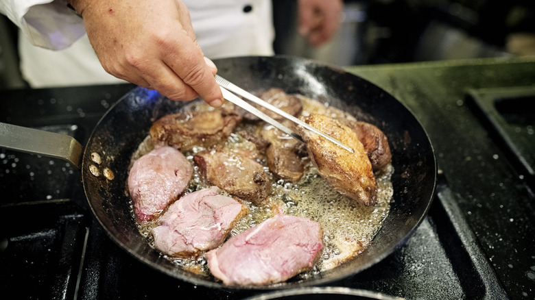 Chef cooking duck breast in skillet