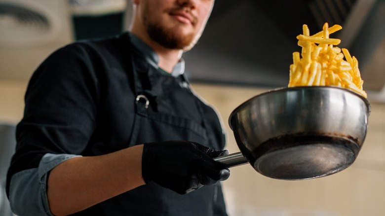 chef flipping french fries in pan