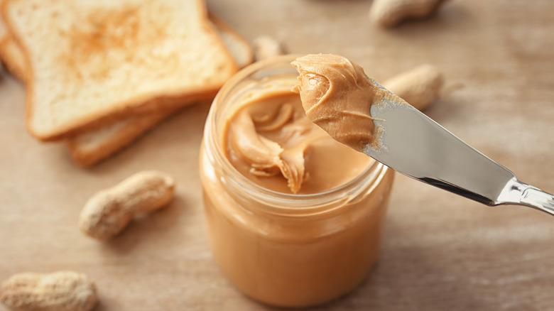 A knife lifting out of a peanut butter jar