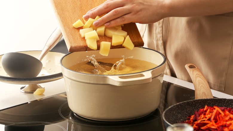 Person sliding potatoes into pot