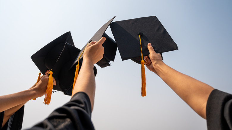 hands holding up a graduation hats