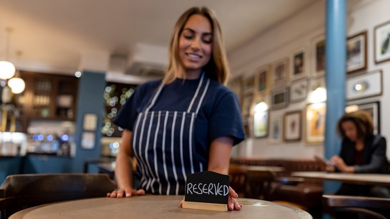 A server placing a reserved sign on table