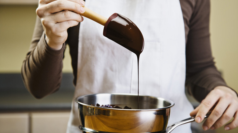 chef in white apron melting chocolate in double boiler