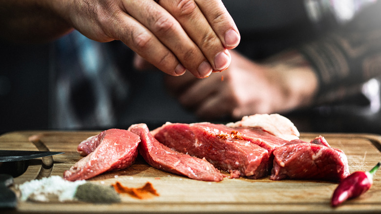 hand seasoning steak slices