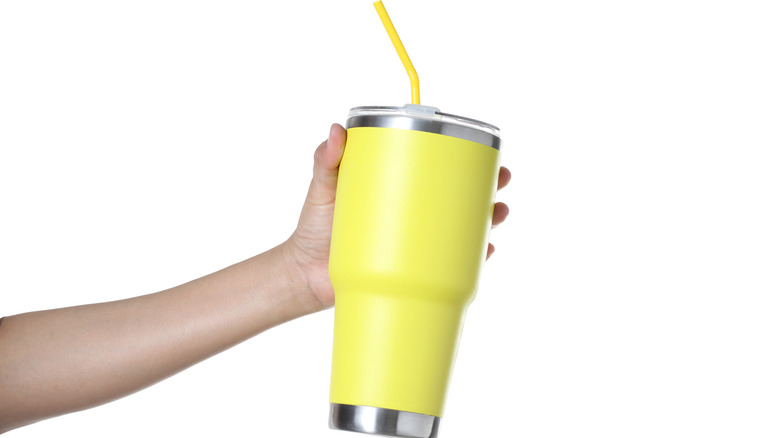 Hand holding yellow tumbler