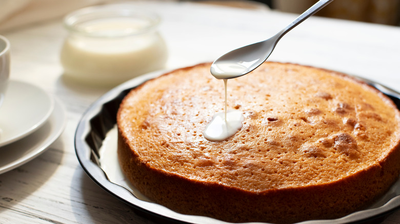 pouring milk on tres leches cake