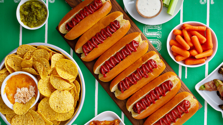 Hot dogs on a tray and snacks in bowls