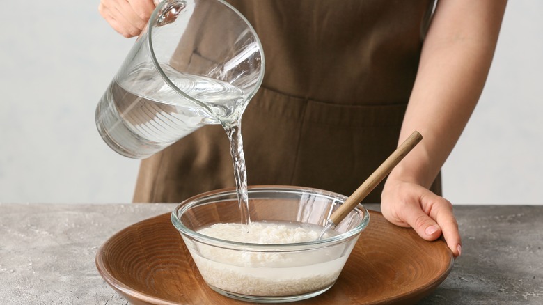 woman pouring water into rice