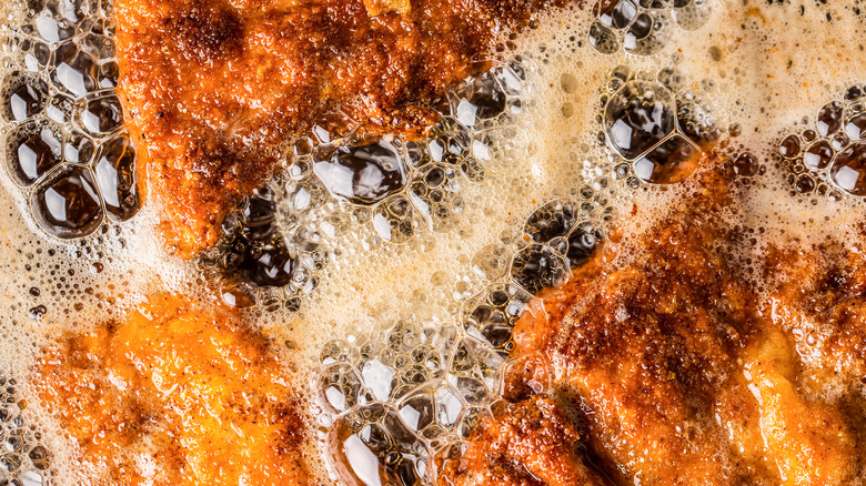 Closeup of chicken frying in a pan.