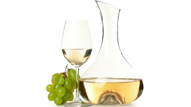 White wine in glass and decanter next to grapes