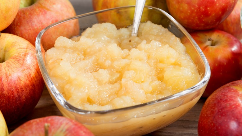 Bowl of applesauce with whole red apples