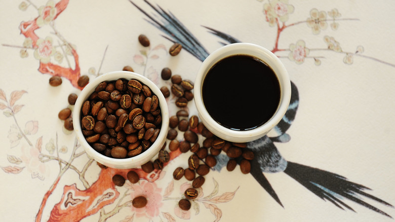 Coffee beans and a brewed cup of coffee on a Chinese design