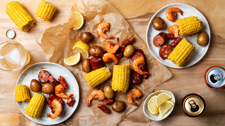 A table of seafood boil, corn, potatoes, and lemons