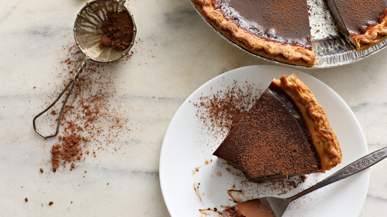 Slice of chocolate pie with cocoa powder on white plate