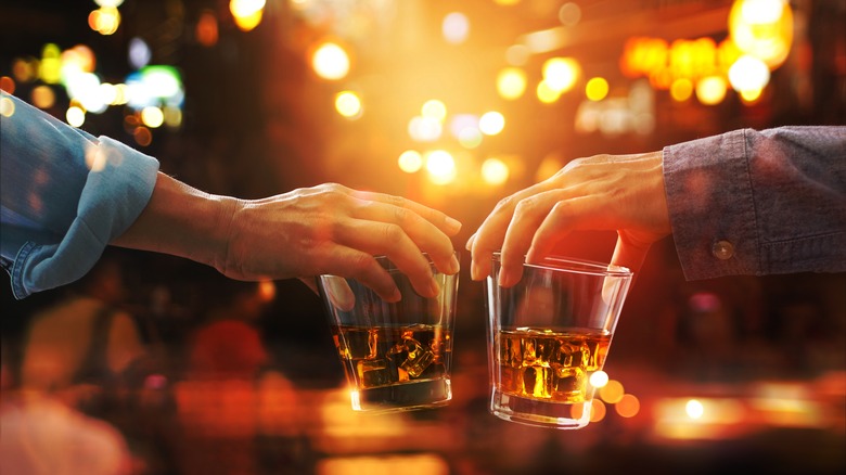 hands holding bourbon glasses