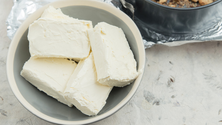 Bowl of cream cheese next to cake pan