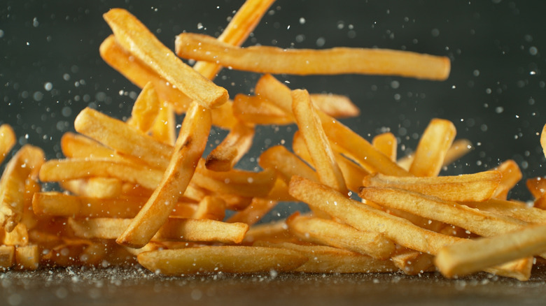 salt falling on pile of French fries