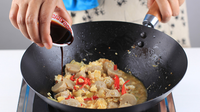 adding sauce to wok 