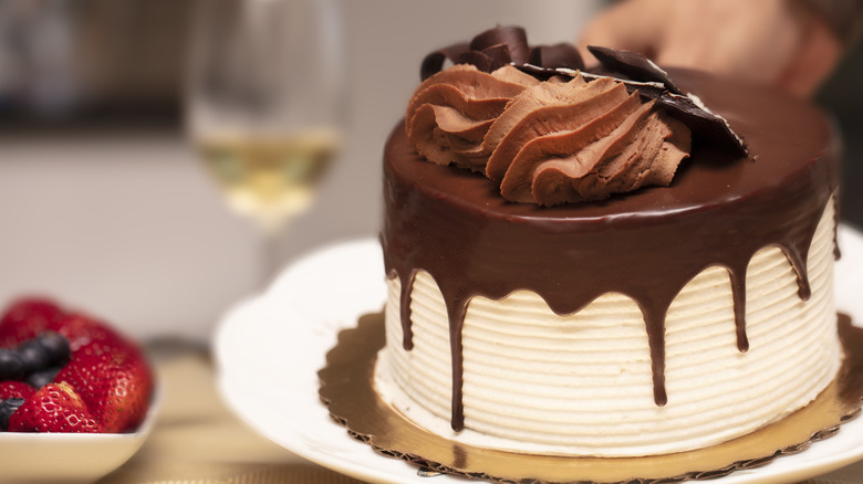 chocolate ganache on vanilla cake next to bowl of berries