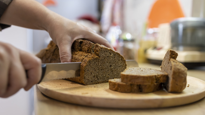 woman slicing brown bread