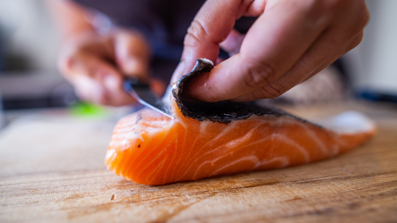 A person slicing fish skin.