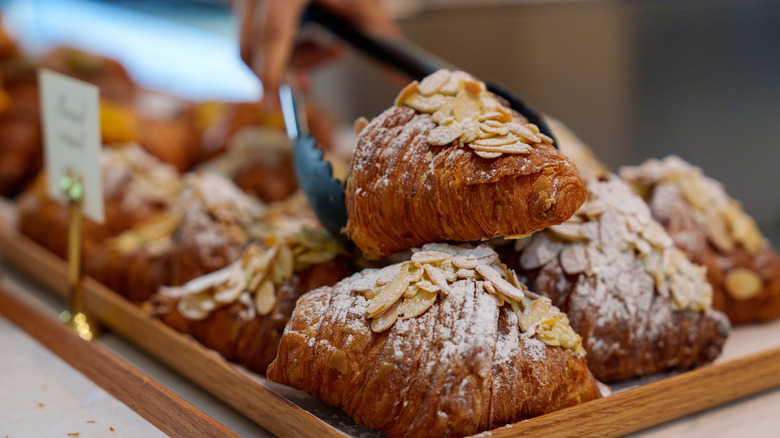 Tongs reaching for almond croissant