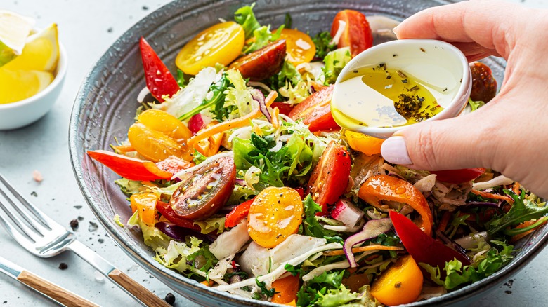 pouring dressing on colorful salad