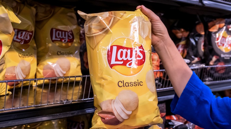 shopper holding bag Frito-Lay's potato chips