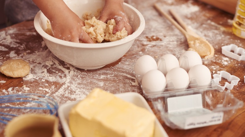 Someone mixing dough by hand with eggs and butter in the foreground