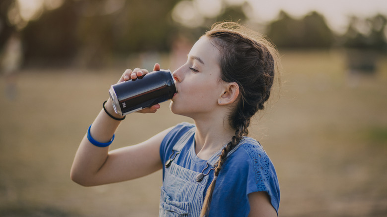 young girl drinking from can