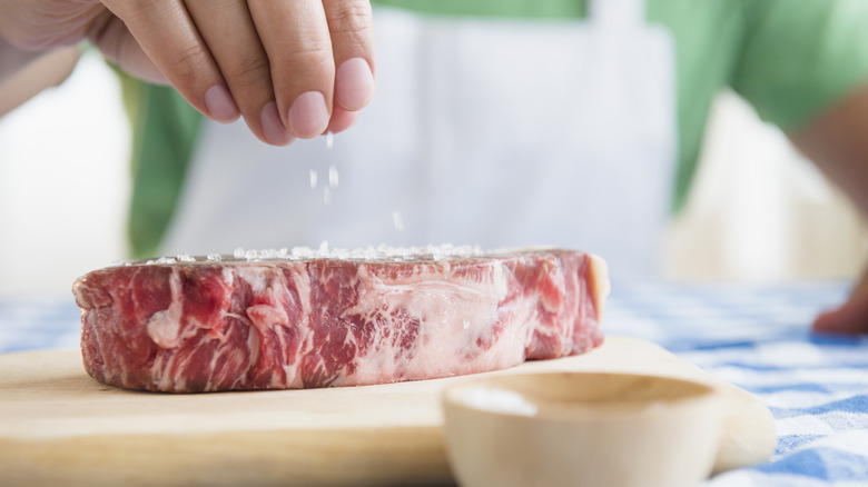 Dropping salt grains on raw steak